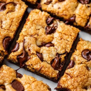 Close-up of chocolate chip cookie bars cut into squares, with golden brown tops and melted chocolate chips visible on the surface.