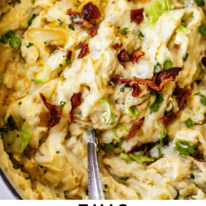 Close-up of creamy Irish colcannon mashed potatoes with green onions and crispy bacon on top, and a metal spoon scooping from the dish. Text overlay: This Irish Colcannon is legit. The Food Charlatan.