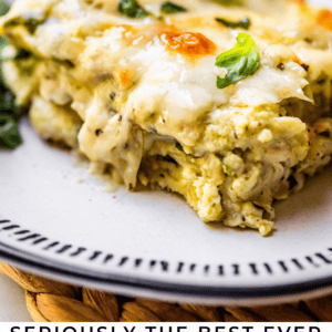 A close-up of a slice of cheesy white chicken lasagna on a plate, garnished with fresh basil, with text below reading Seriously the best ever White Chicken Lasagna - The Food Charlatan.