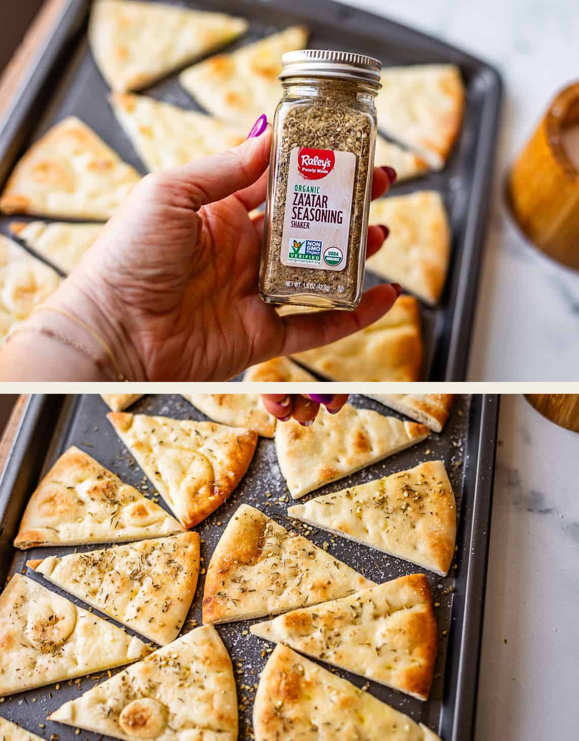 A hand holds a jar of zaatar seasoning over a baking tray filled with sliced, baked flatbread pieces. The flatbread triangles on the tray are sprinkled with zaatar.