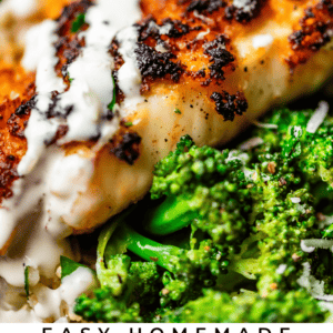 Close-up of a crispy, golden-brown parmesan-crusted tilapia fillet topped with a creamy white sauce, served on a bed of bright green broccoli. Text overlay reads: “Easy Homemade Parmesan Crusted Tilapia - The Food Charlatan.”.