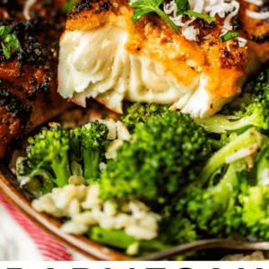 Close-up of a piece of parmesan-crusted tilapia topped with grated cheese and parsley, served alongside steamed broccoli and a lemon wedge. Text at the bottom reads Parmesan Crusted Tilapia – The Food Charlatan.