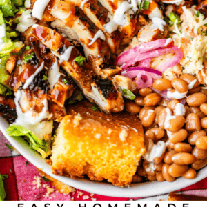 A colorful BBQ chicken bowl topped with grilled chicken, corn, beans, lettuce, pickled onions, and a drizzle of white sauce, served with a piece of cornbread. Text reads Easy Homemade BBQ Chicken Bowls The Food Charlatan.