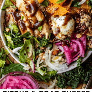 A bowl of green salad topped with citrus slices, goat cheese, grilled chicken, pickled onions, and drizzled with dressing, surrounded by small bowls of salad ingredients.