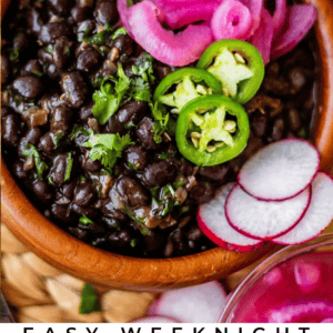A bowl of Mexican black beans topped with pickled onions, sliced jalapeños, and fresh herbs, served with sliced radishes nearby. The image is labeled Easy Weeknight Mexican Black Beans..