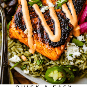 A plate with chili lime blackened salmon on green rice, topped with sauce and herbs, served with black beans, pickled onions, jalapeños, and cheese. Text: Quick & Easy Chili Lime Blackened Salmon. The Food Charlatan.