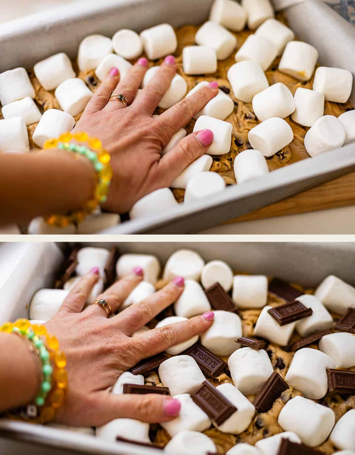 A hand presses marshmallows onto cookie dough in a baking pan. In the next image, chocolate pieces are added among the marshmallows. The hand wears colorful bracelets and has pink nail polish.