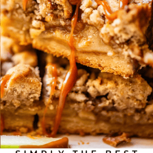 Close-up of gooey apple pie bars with crumb topping and caramel drizzle, stacked on top of each other. Text below reads: SIMPLY THE BEST APPLE PIE BARS THE FOOD CHARLATAN.
