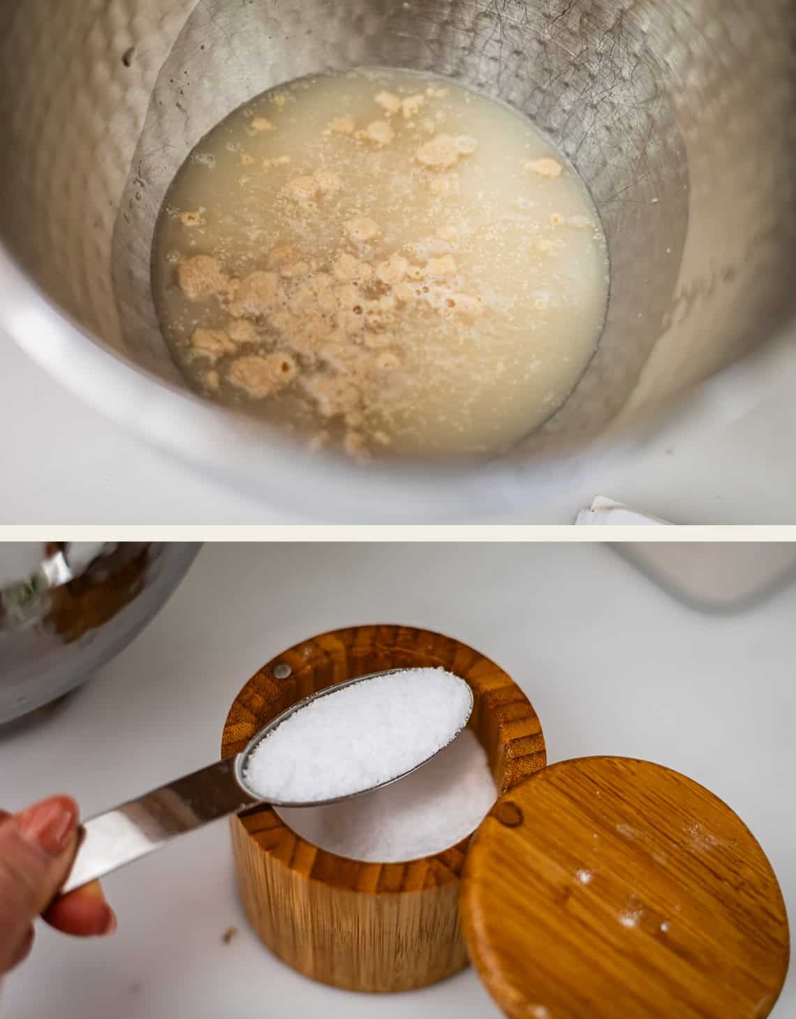 A metal mixing bowl containing water and yeast, and a hand holding a measuring spoon filled with salt over a wooden salt cellar.