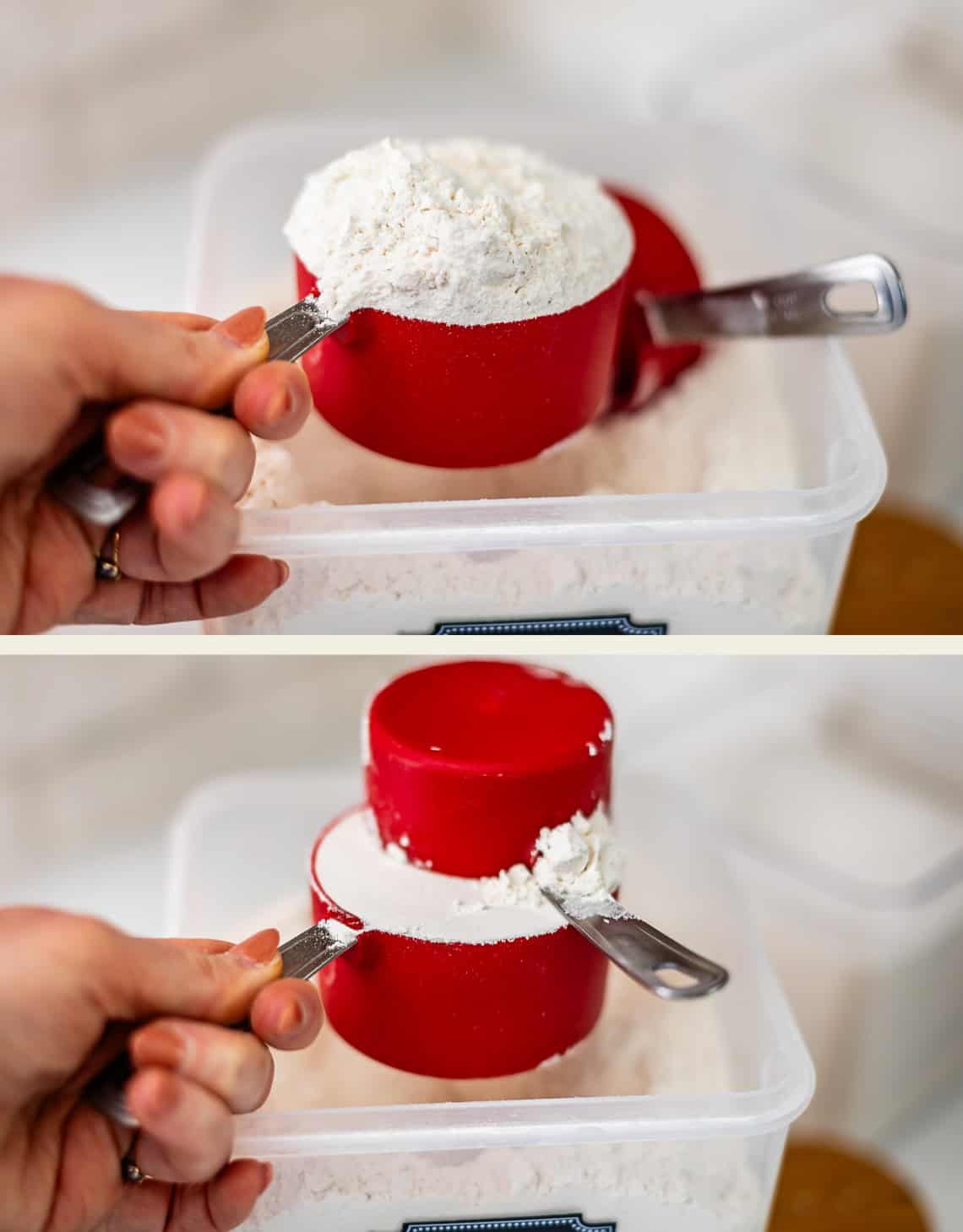 A hand holds a red measuring cup filled with flour over a storage container, showing the process of leveling off the scoop.