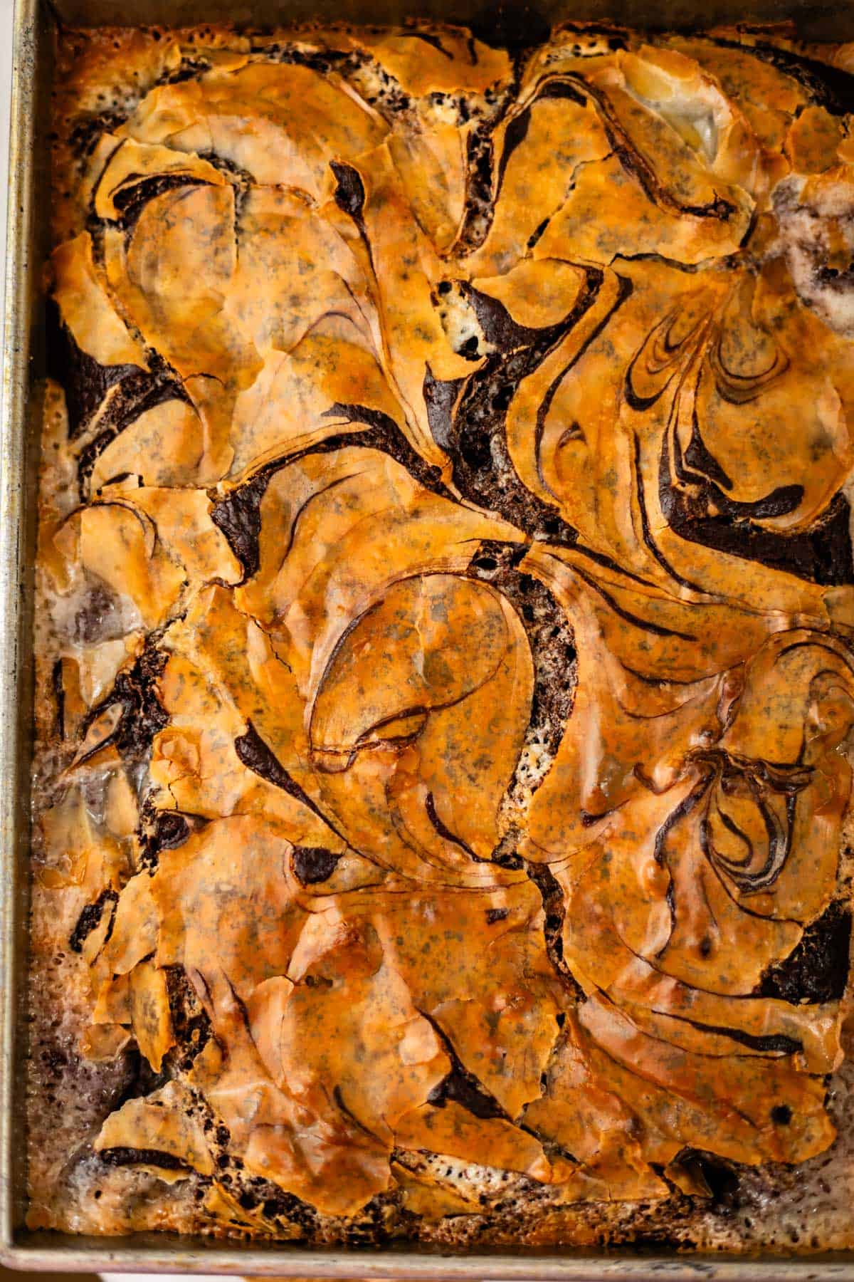 A rectangular tray of baked brownies with a swirled pumpkin or caramel topping.