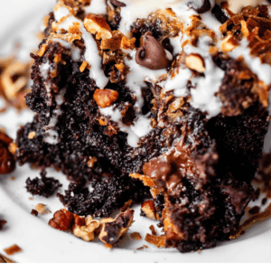 A slice of chocolate cake topped with pecans, chocolate chips, and a scoop of vanilla ice cream, labeled with the text Cream Cheese Earthquake Cake.