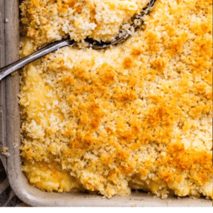 A baking dish of mac and cheese topped with breadcrumbs, with a serving spoon scooping out a portion. The text below says Weeknight Mac and Cheese, The Food Charlatan.