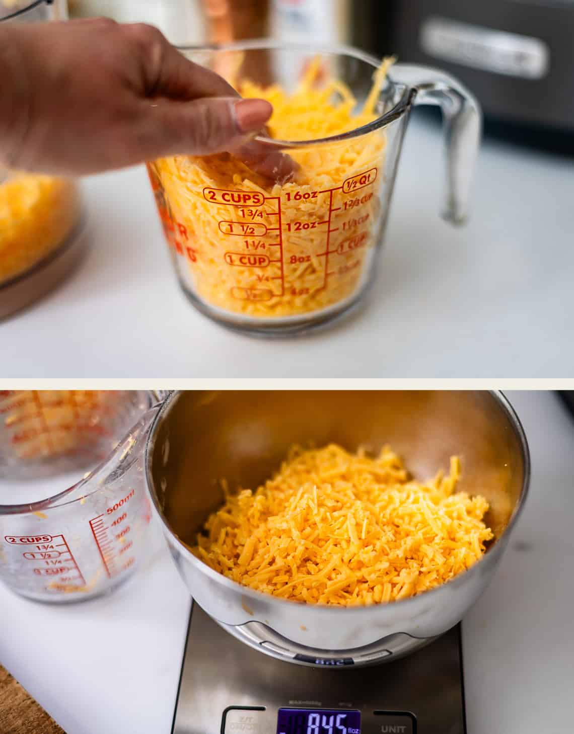 A hand presses shredded cheddar cheese into a glass measuring cup, and a mixing bowl filled with shredded cheese sits on a digital kitchen scale.